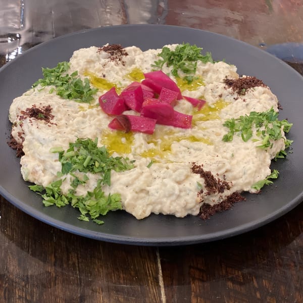 Creamy baba ghanoush topped with parsley, sumac, olive oil, and bright pink pickled turnips.